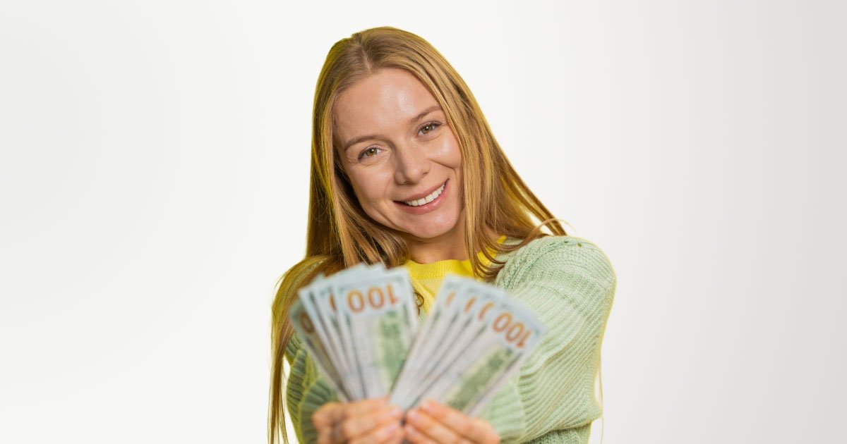 Photo of blonde haired woman holding hundred dollar bills out in front of her with yellow backdrop