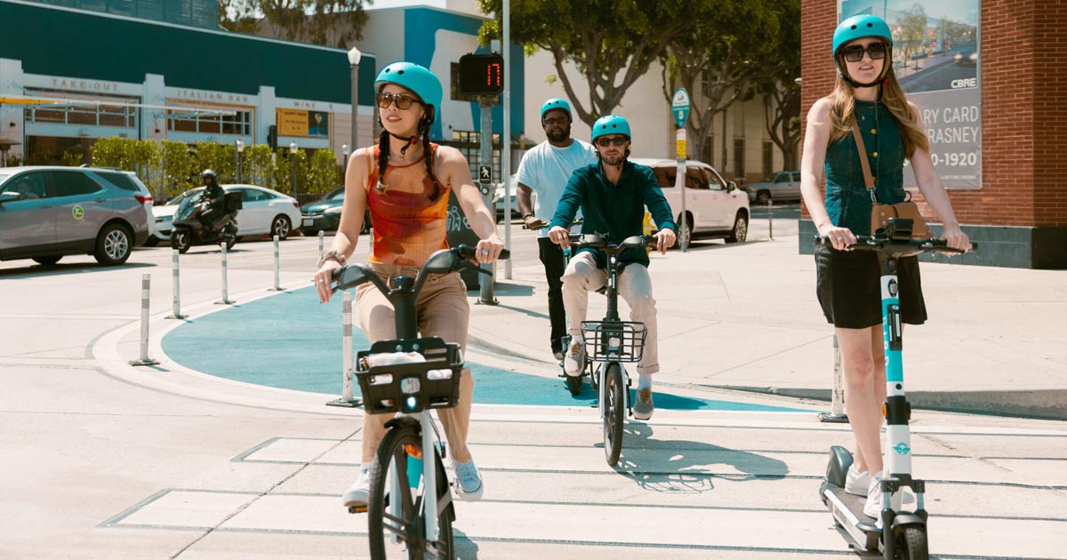 Group of friends riding around town on scooter and bike rentals