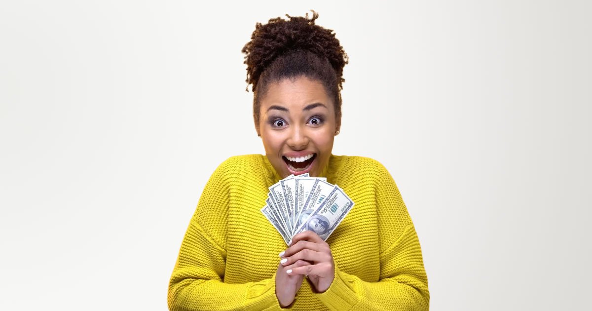 African American woman excited to be holding handful of cash showing it off wearing a yellow sweater with a yellow backdrop