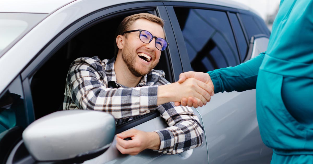 Local resident shaking hands with man who is buying his car