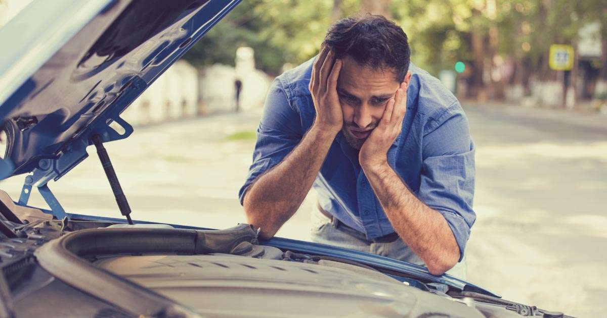 Man staring at his car's engine in disbelief