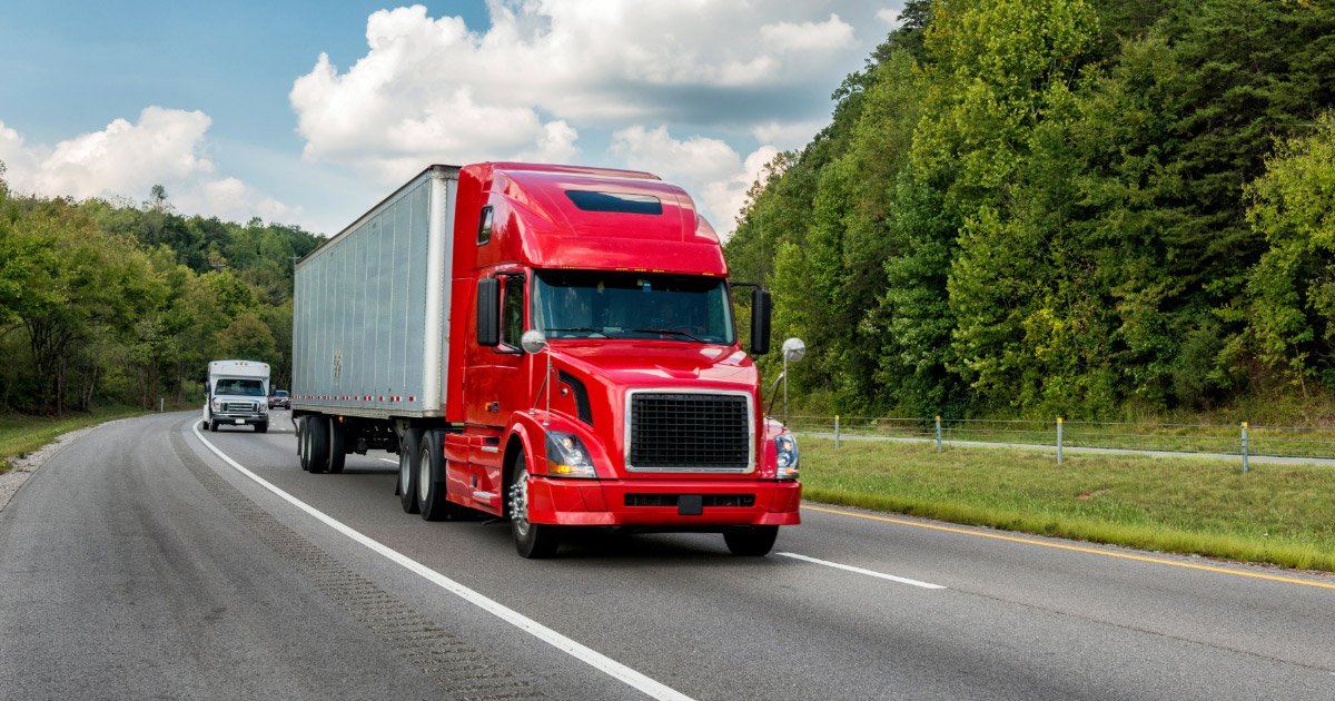Semi-truck with red cab and white trailer traveling down Virginia highway