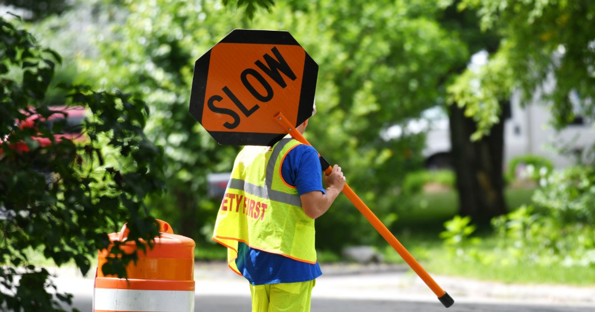 Road worker holding Slow sign to help regulate traffic speeds
