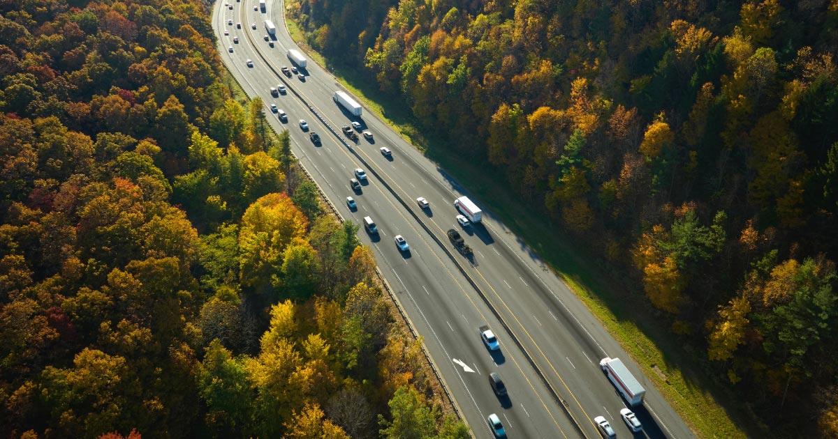 Highway in forested area with multiple lanes of traffic heading in both directions