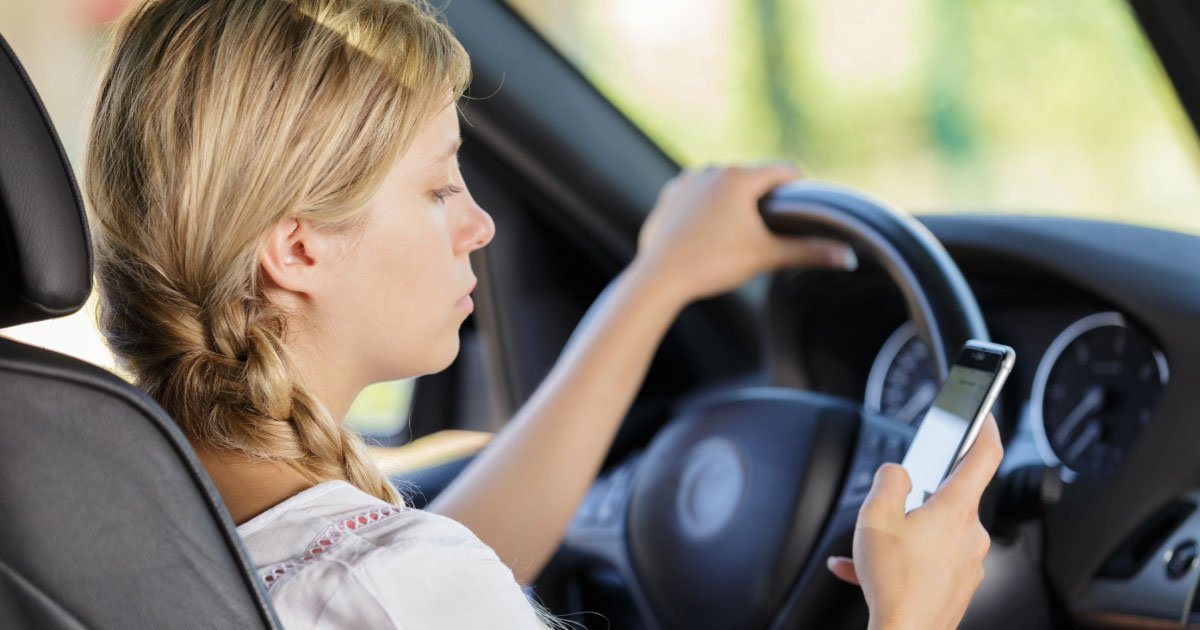 Woman looking at her phone texting while driving
